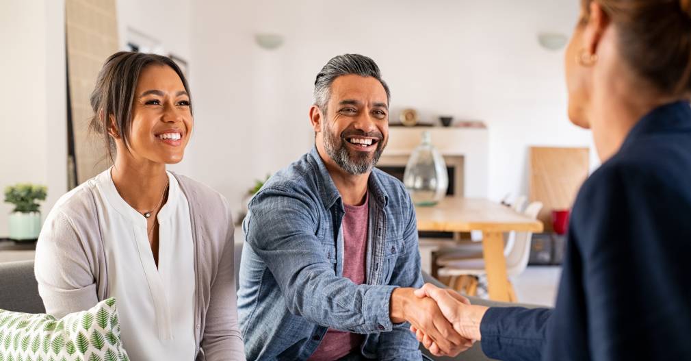 Photo of a financial planner shaking hands with a happy couple.