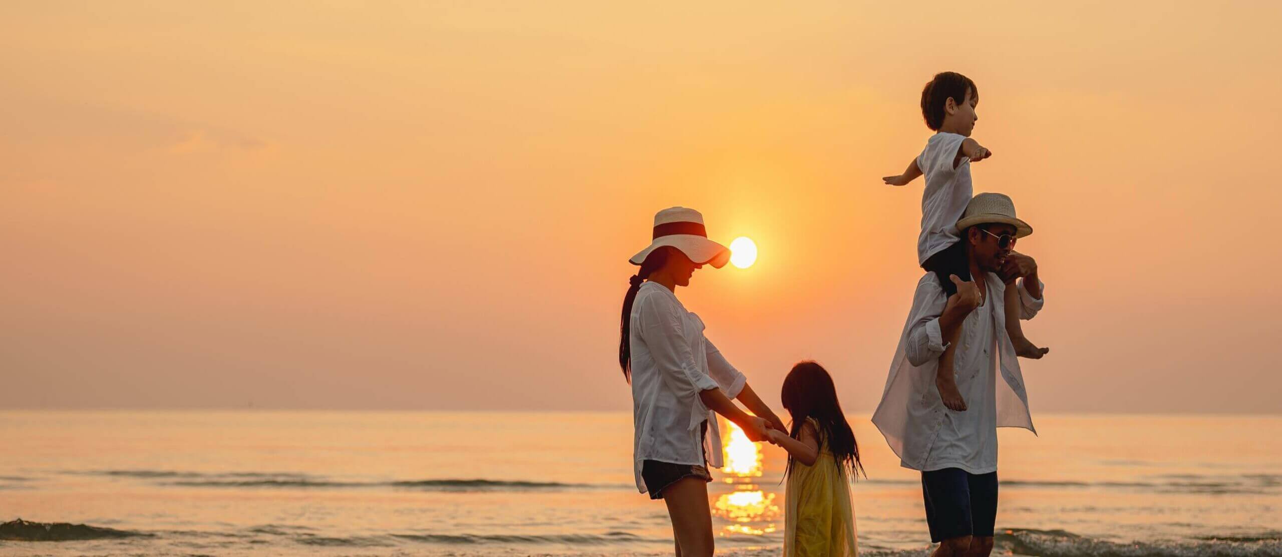 Scenic photo of a financially independent family walking on the beach at sunset.